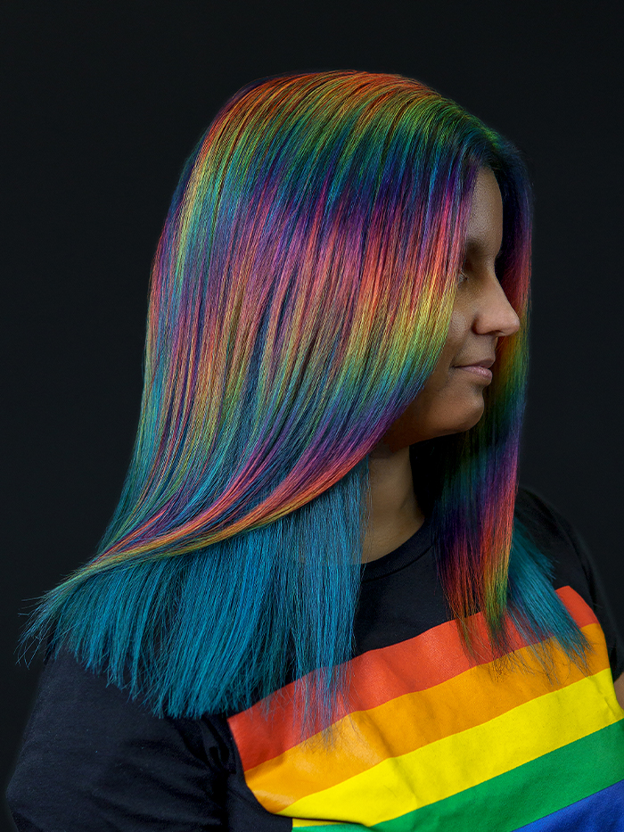 Young woman with rainbow prism hair colour, featuring pink, orange, yellow, green, blue, and purple tones using Danger Jones hair colour.