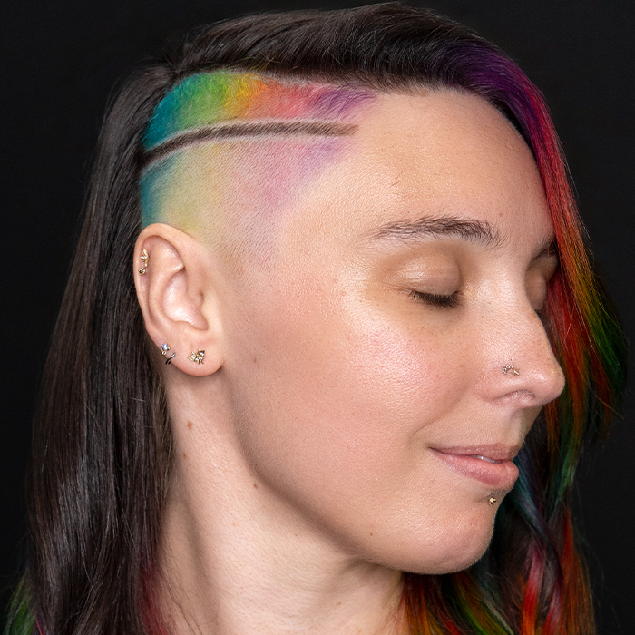 Young woman with undercut hairstyle, prism rainbow colour placement and watercolour-inspired vivid tones, created using Danger Jones hair colour.