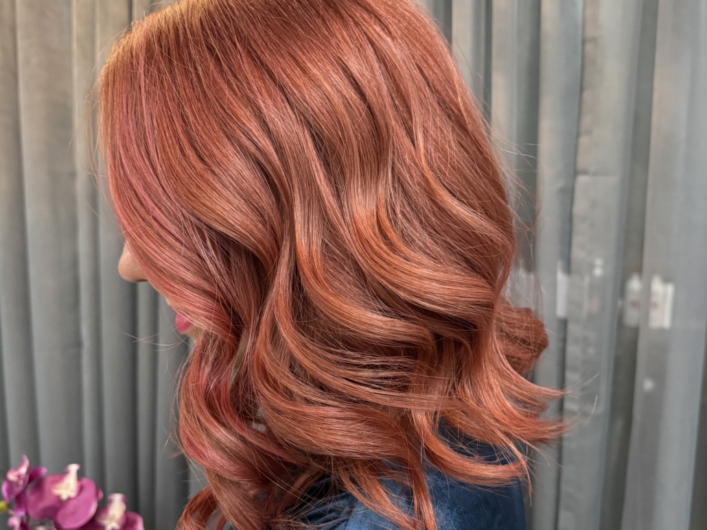 smiling woman with rose gold hair color in salon
