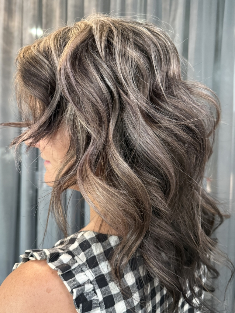 woman with curled hair coloured a grey-beige in salon