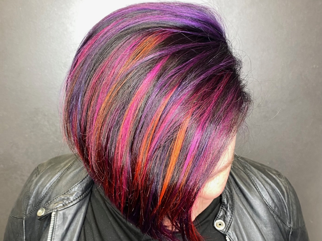 young woman with black pink orange and purple colored hair in salon
