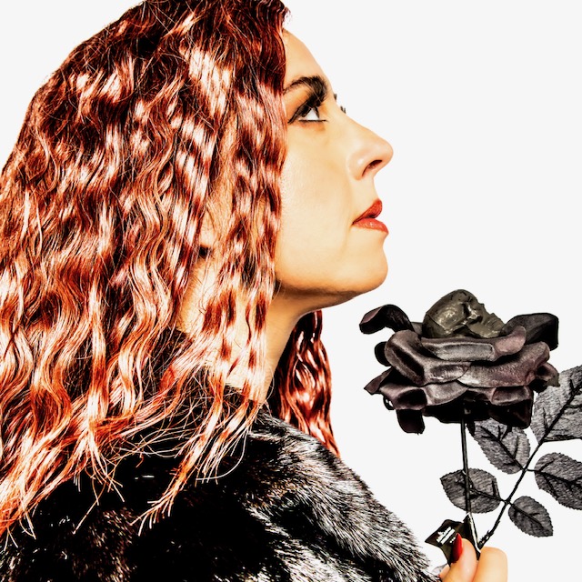woman with rose-gold colored hair holding a black rose