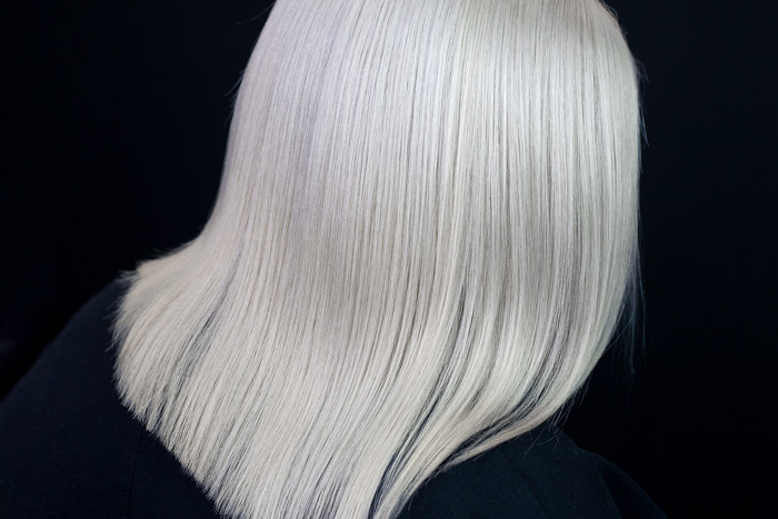 young woman with perfectly clean white hair on dark background in salon pulp riot