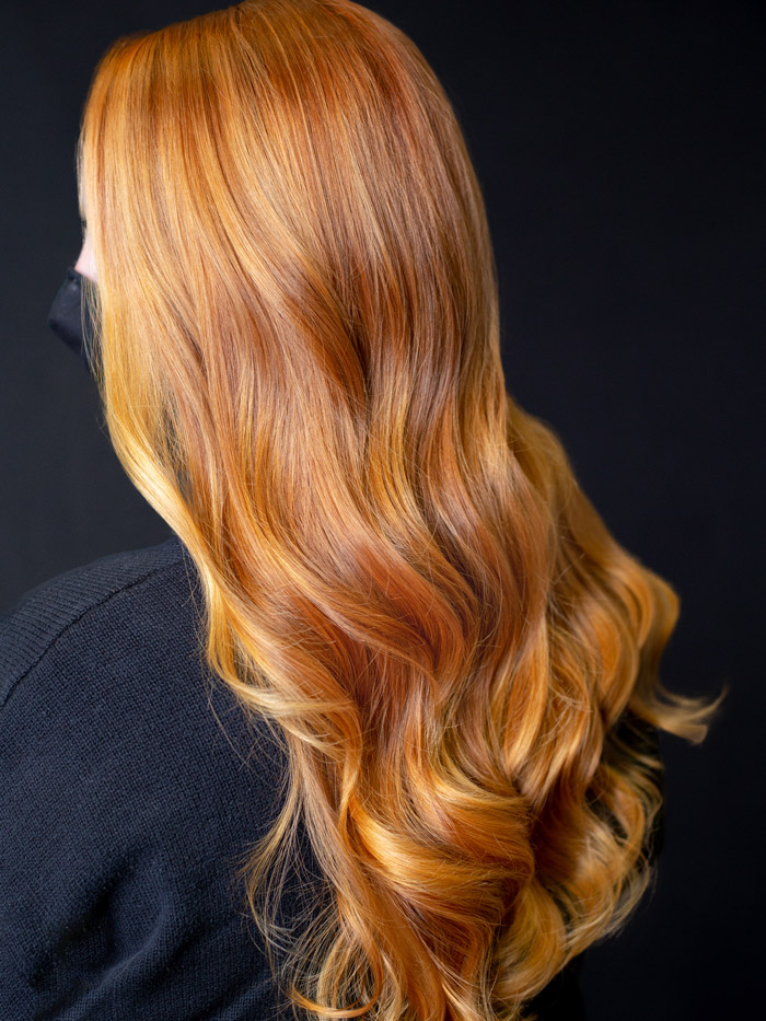 woman with wavy orange hair in salon with black background