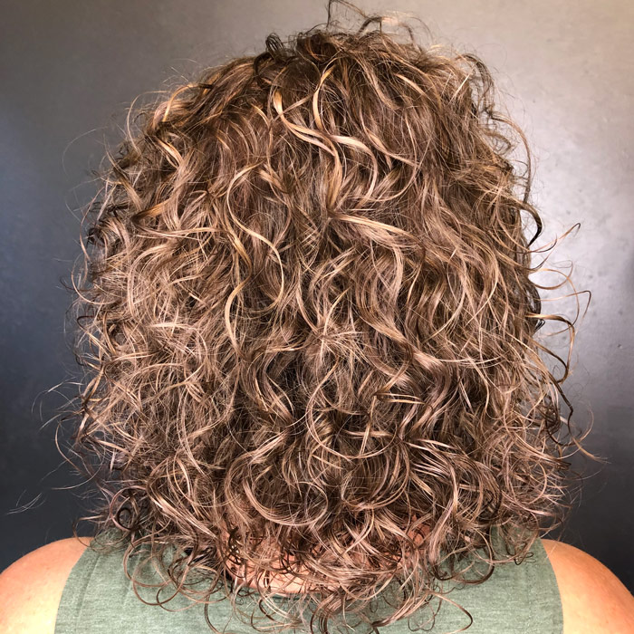 middle aged woman with curly sand brown hair in salon