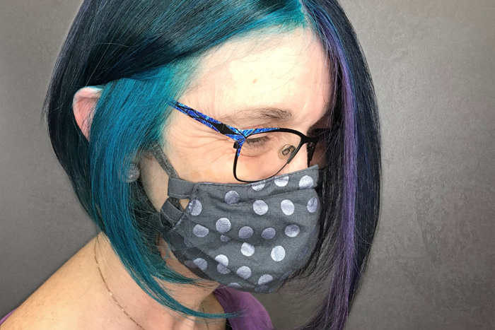 middle aged woman with glasses and teal blue hair colour in salon