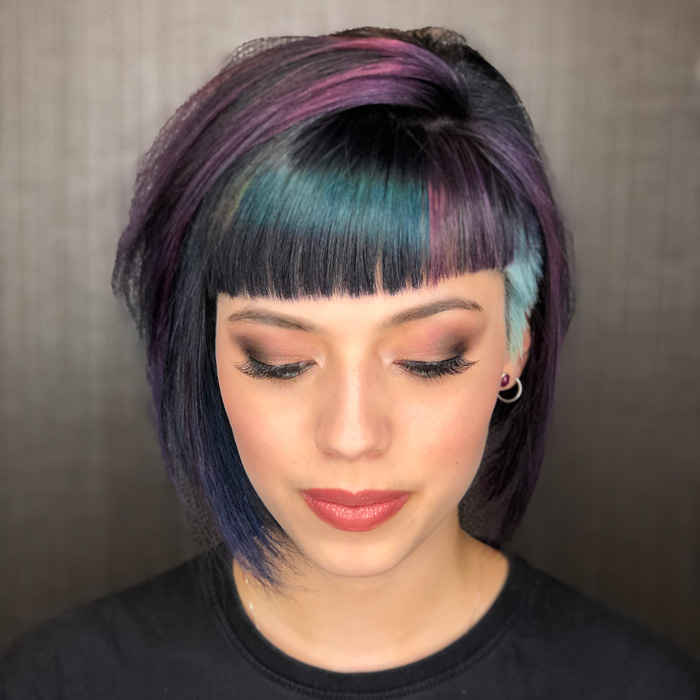 young woman with short styled black and grey and purple coloured hair in salon