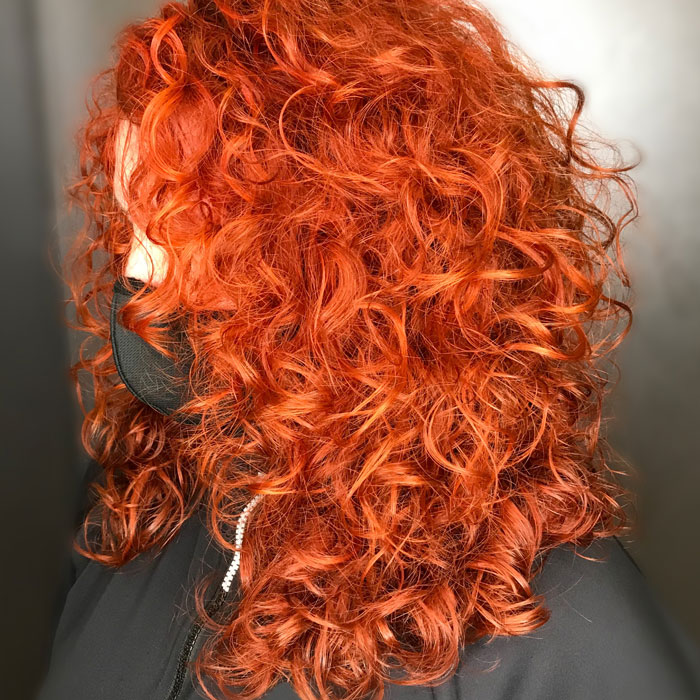 woman with bright orange red curly hair in salon