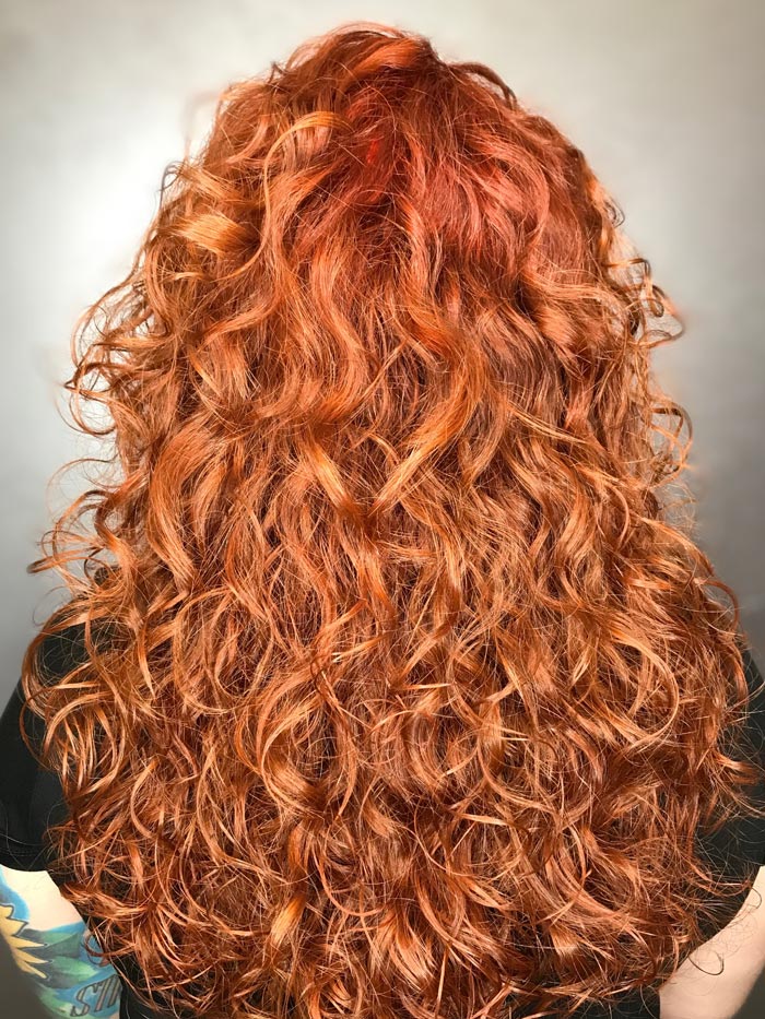 woman with bright fire red curly hair in salon