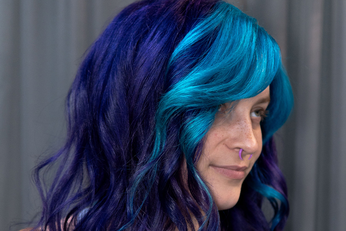 Young woman with deep purple hair and bright neon blue-teal bangs, coloured using Danger Jones hair colour.