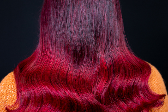 Young woman with dark roots blending into vibrant velvet-crimson lengths and balayage-inspired highlights, created using Danger Jones hair colour.