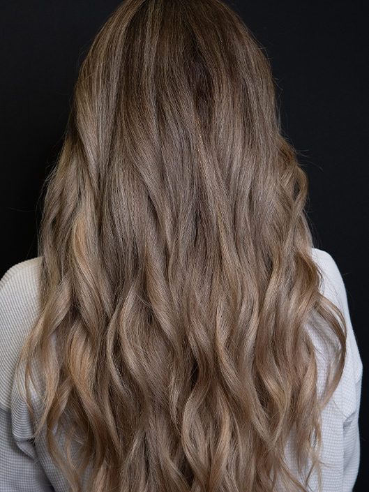 Young woman with lived-in beach blonde hair and softly blended balayage highlights, creating natural-looking dimension.