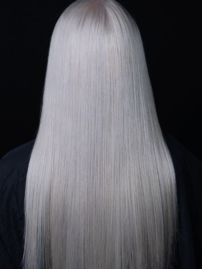Young woman with long, sleek platinum white blonde hair, evenly coloured from roots to ends and styled straight.