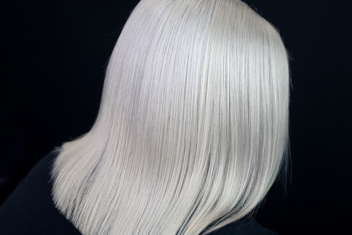Older woman with sleek platinum white hair in a shoulder-length blunt bob, styled straight with softly curved ends.
